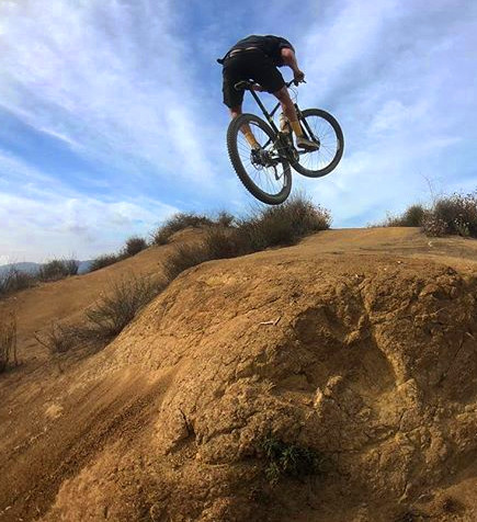 Dave doing a stunt jump up a dirt ramp