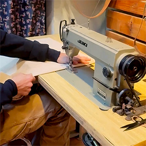 Person sewing window treatment fabric with a sewing machine