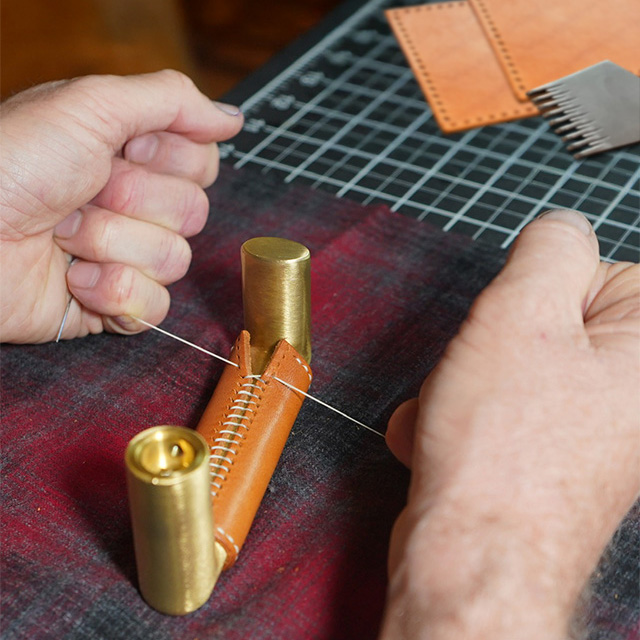 Hand stitching leather wrap around a brass door handle
