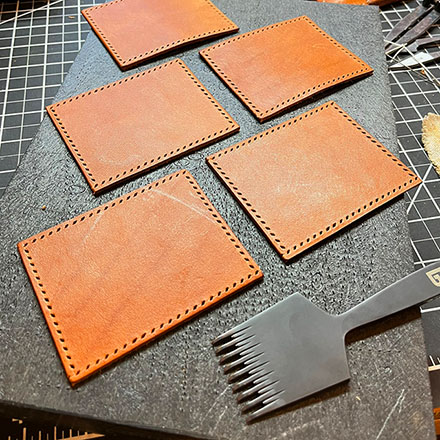 Leather square pieces cut out with hand-punched holes for stitching