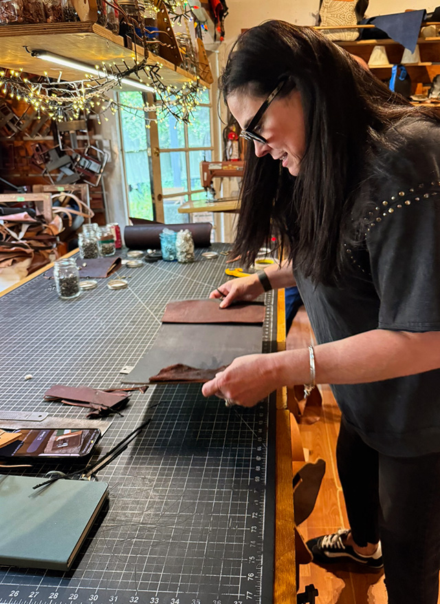 Woman making a leather journal cover at a crafting table
