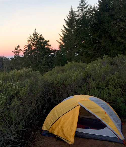 Chris camping with his tent at sundown.