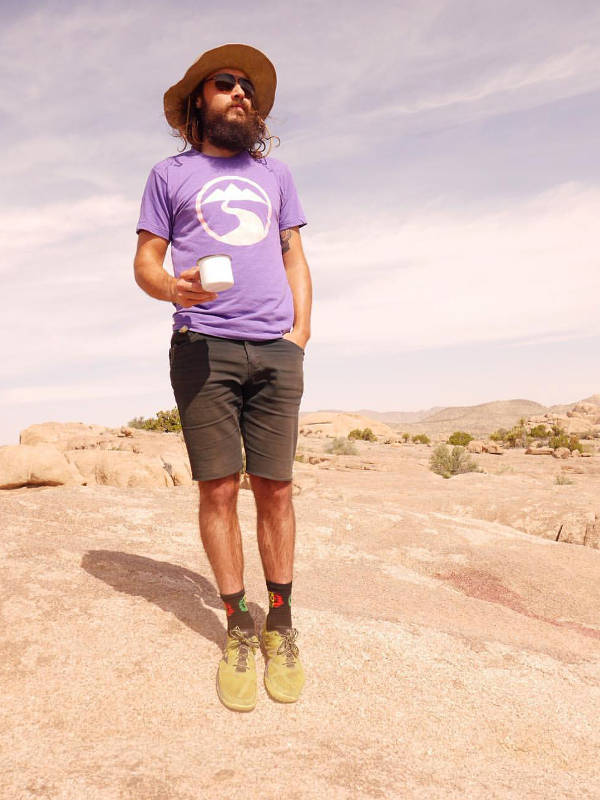 Jay standing in the wilderness while holding a mug and looking into the distance.