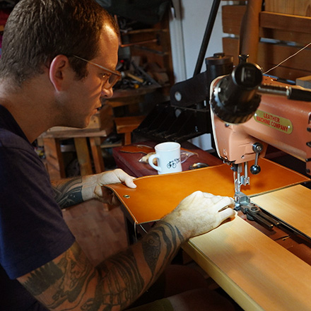 Leathersmith sewing the edges of leather folio with a sewing machine
