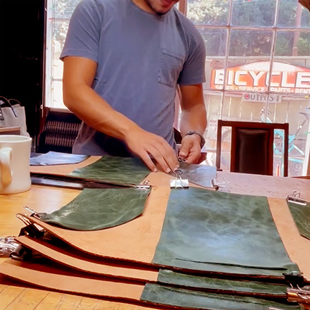 Leathersmith attaching the pocket to the leather folio