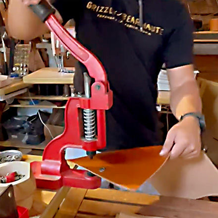 Leathersmith pressing the metal grommet into the leather folio