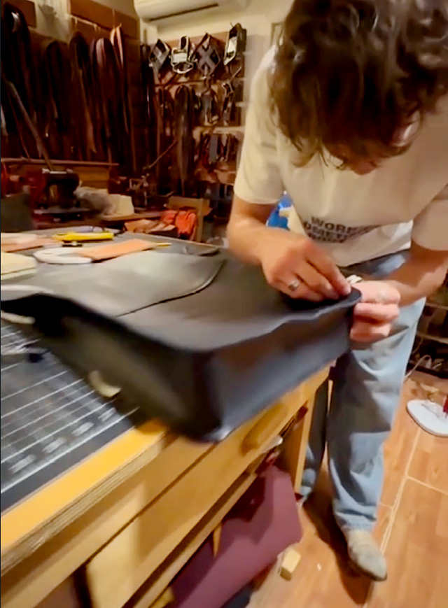 Guy crafting a leather shoulder bag on a table