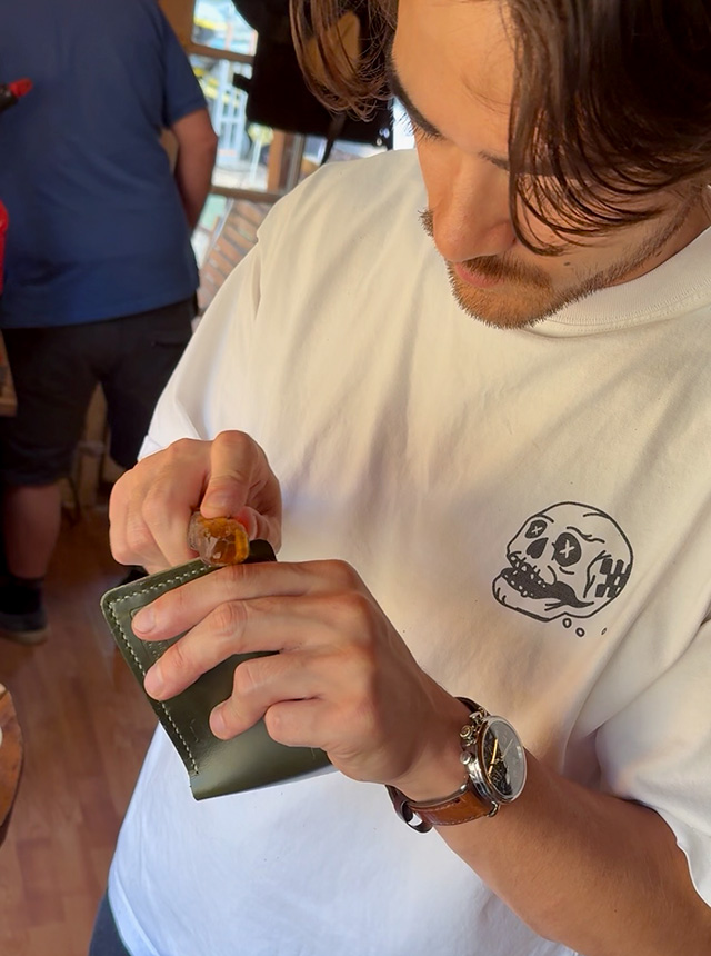 Guy burnishing the edge of a wallet he's in the middle of making